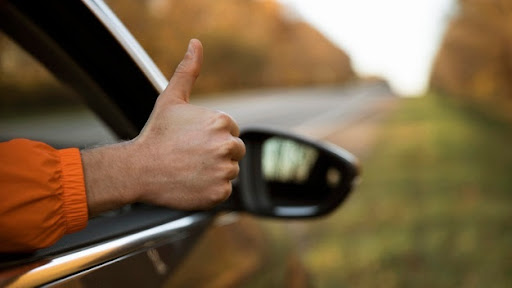 Ręka wystająca z samochodu z kciukiem do góry - gestem ok. 